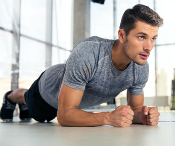 Portrait of a fitness man doing planking exercise in gym
